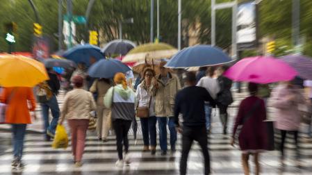 Varias personas se protegen de la lluvia caída este jueves en Zaragoza