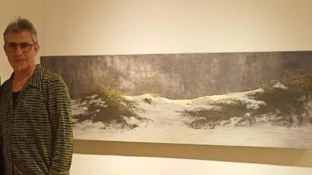 El artista riojano Juan José Ortega, junto a uno de los paisajes nevados que forman parte de la exposición que presenta en Pamplona