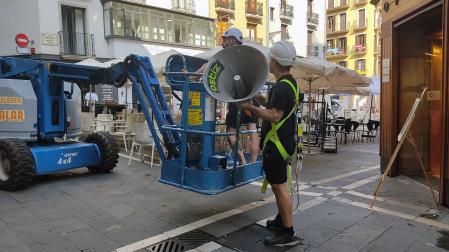Dos operarios trabajan en la colocación de la megafonía en la plaza del Ayuntamiento de Pamplona