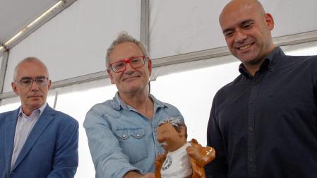 El director de la Semana Negra de Gijón, Ángel de la Calle (c) exhibe el "Rufo", la estatuilla que se entrega a los ganadores del certamen literario, que este año reproduce la figura del fundador del festival, el escritor hispano mexicano Pacho Ignacio Taibo II