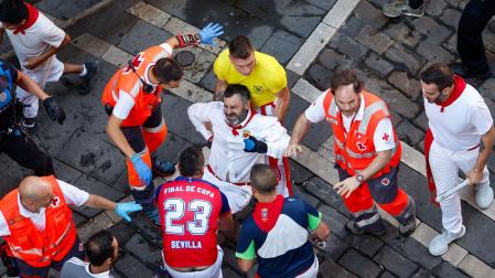 Mozos y sanitarios trasladan a un herido durante, durante el octavo y último encierro de sanfermines este viernes en Pamplona con los legendarios toros de la ganadería de Miura