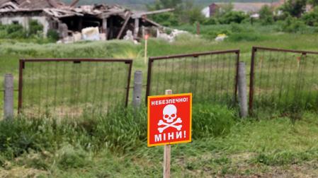 Una señal de ''¡Precaución! Minas'' en la zona de pruebas de una máquina de desminado humanitario construida sobre la base de un tractor T-150 por ingenieros de Kharkiv, región de Kharkiv, noreste de Ucrania.