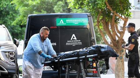 Miembros de los servicios funerarios trasladan el cadáver de la joven asesinada esta tarde en el barrio de Pescadería de Almería, degollada presuntamente por su pareja