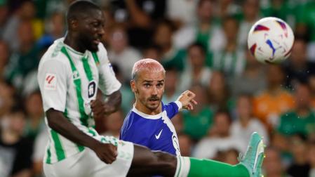 El delantero del Atlético de Madrid Antoine Griezmann centra el balón junto a Youssouf Sabaly, del Betis