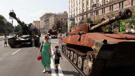 Varias personas caminan entre vehículos militares rusos dañados y tomados por el ejército ucraniano en Kiev