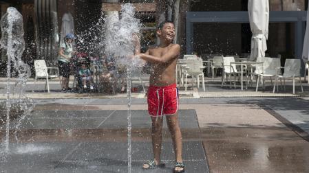 Un niño, refrescándose este martes al mediodía en los chorros de agua de la pamplonesa plaza de Yamaguchi