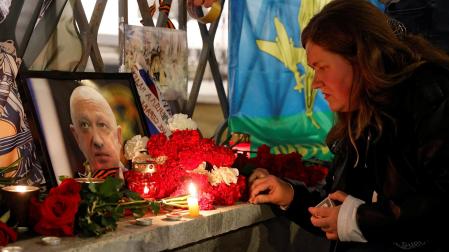 Una mujer enciende una vela frente a un retrato del jefe de los mercenarios de Wagner, Yevgeny Prigozhin, en un monumento improvisado en Moscú, Rusia