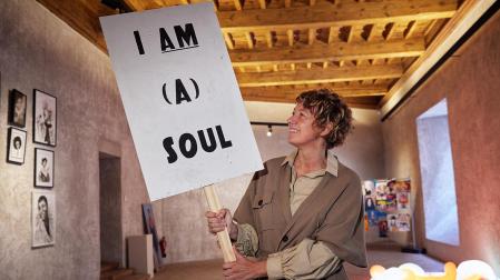Ángela Laurenz, sujetando el cartel con el título de la exposición, I am (a) soul, en el Palacio de Condestable