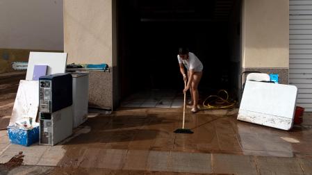 Una mujer limpia su vivienda tras las lluvias en Tarragona