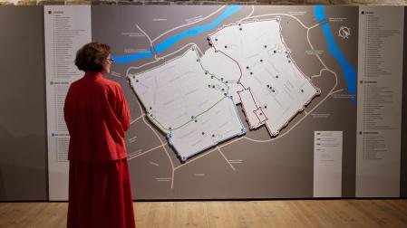La directora del Museo de Navarra, Mercedes Jover, invitada a la inauguración, contempla el mapa de los tres burgos de Pamplona que puede verse en la exposición
