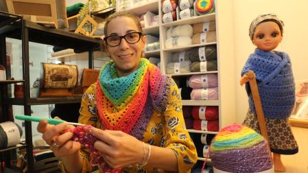 Lluna Barquero tejiendo una bufanda de colores en su nueva tienda.