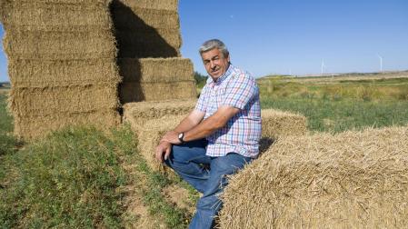 Roberto Francés Clemos, sentado en unas pacas de paja en su almacén de Fontellas