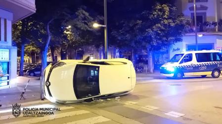 Vehículo volcado entre las calles Amaya y San Fermín tras colisionar contra un protector de acera