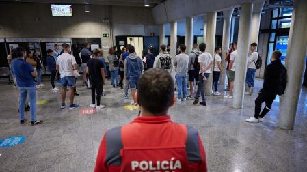 Un agente de la Policía Foral, junto a los aspirantes, en la entrada al Aulario de la UPNA.