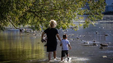 Una mujer y un niño se refrescan en las aguas del Arga, junto a las pasarelas de la Magdalena.