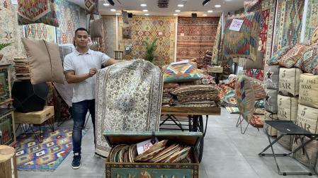 John, dependiente de House of Kilim, muestra una alfombra de seda