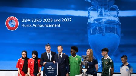 El presidente de la UEFA, Aleksander Ceferin, muestra el nombre del Reino Unido e Irlanda elegidos para albergar la Eurocopa 2028 junto a Gareth Bale, futbolista galés y embajador durante la ceremonia de anuncio de los países organizadores