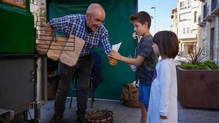 El castañero entrega un cucurucho de castañas a dos niños