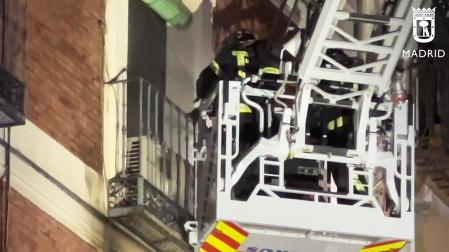 El camión escala de los bomberos trabaja en la fachada del inmueble que se incendió