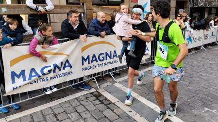 Uno de los participantes se acerca a la meta con una niña en brazos acompañado por otro corredor