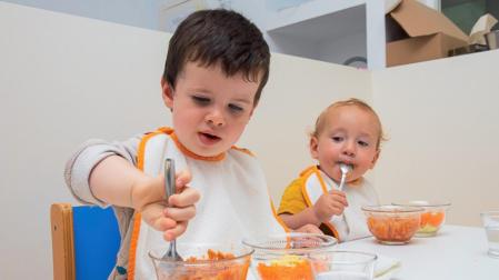 Dos menores incluidos en el proyecto ELIKUME comen en uno de los comedores infantiles