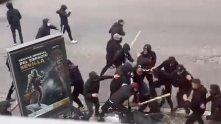 Un momento de la brutal paliza que varios ultras propinan con palos y barras a una persona que se queda inmóvil en el suelo junto a una moto este domingo en Sevilla