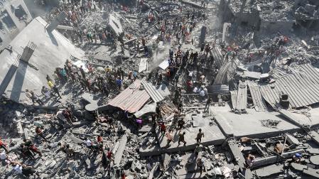 Palestinos buscan supervivientes entre los escombros de un edificio de viviendas alcanzado en un ataque israelí en el campo de refugiados de Khan Younis