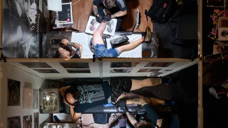 Dos de los tatuadores trabajan en sus obras durante el Pamplona Tatoo Expo del Baluarte