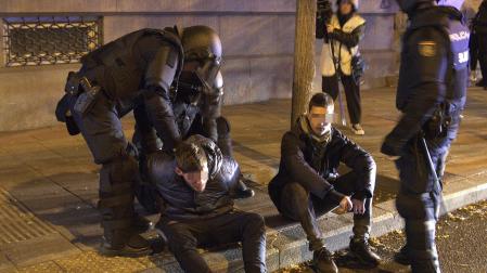 Agentes de la Policía Nacional esposan a dos de los detenidos tras los incidentes ante la sede del PSOE en Ferraz
