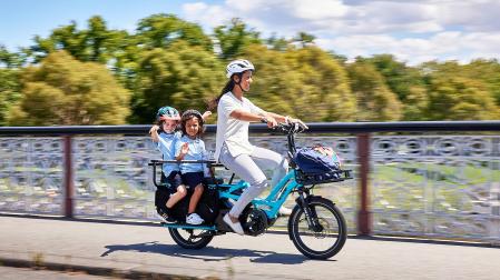 Una mujer lleva a dos menores en una bicicleta eléctrica