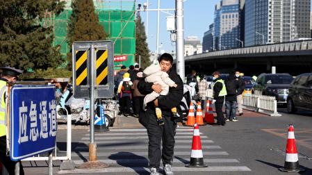 Un padre acude a un centro de salud con su hijo menor en brazos en Pekin, la capital china./