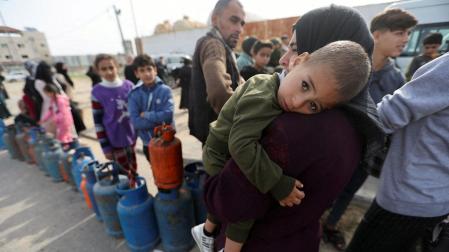 Una mujer porta en brazos a su hijo en un puesto de recogida de bombonas de gas al sur de la Franja de Gaza