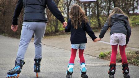 Dos niñas patinando con un adulto