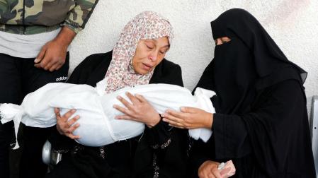 Dos mujeres palestinas, junto al cuerpo sin vida de un niño gazatí