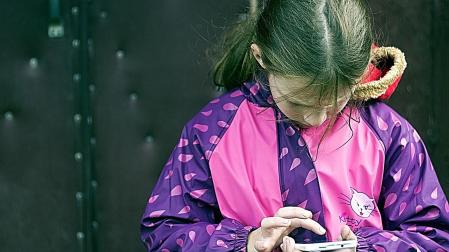 Una niña con un móvil en un recreo