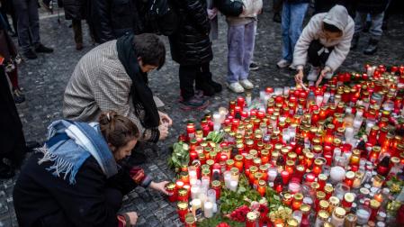 Varias personas encienden velas en la Universidad Carolina de Praga, donde tuvo lugar el tiroteo este 21 de diciembre