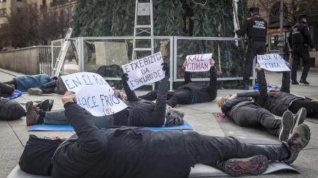 Representantes de Mugak Zabalduz se han echado en el suelo sobre esterillas mostrando carteles