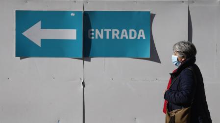 Una mujer con mascarilla camina en el entorno de un centro de salud de Madrid
