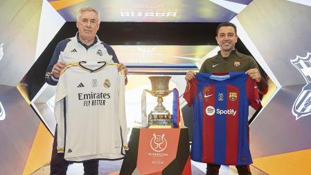 Carlo Ancelotti y Xavi Hernández, entrenadores del Real Madrid y Fútbol Club Barcelona respectivamente, posan con las camisetas de sus equipos en un acto previo a la gran final de este domingo.