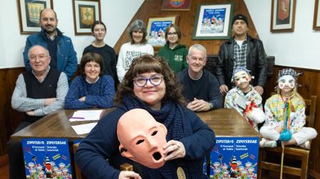 La Zipotera Mayor del Carnaval de Tudela 2024, Ane Domínguez Marco, posa con una máscara en la sede de la peña Beterri ante parte de los miembros de la Asociación de Amigos de los Zipoteros de la capital ribera