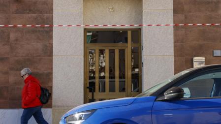 Una persona pasa por delante del portal de la vivienda donde se ha encontrado el cuerpo de la mujer