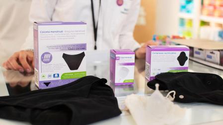 Una farmacéutica muestra las bragas menstruales, la copa menstrual y las dos compresas de tela que todas las mujeres de Cataluña ya pueden escoger y recoger gratuitamente en las farmacias