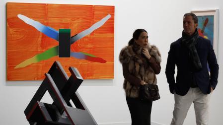 Dos personas pasan ante la obra de José Manuel Broto 'Relatos X' 2022 (acrílico sobre lienzo) en la feria de arte contemporáneo ARCO