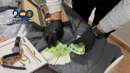Un agente de la Policía Nacional cuenta dinero incautado y joyas durante la operación contra la banda que asaltaba viviendas de lujo en Madrid./