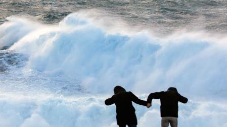 Dos turistas observan el oleaje en la cosa de Muxía, este miércoles en A Coruña