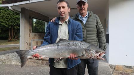 Gonzalo Díaz Soto (i), pescador de Cangas de Narcea, que posa junto a su ganchero. El ejemplar ha pesado 8,2 kilos y mide 92 centímetros