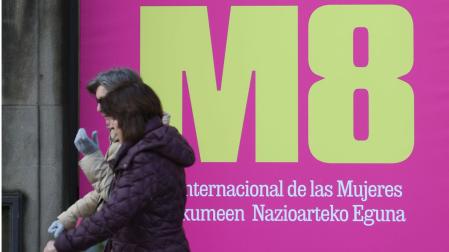Dos personas pasan por delante de un cartel de la campaña lanzada con motivo del Día Internacional de la Mujer, habitual entre las acciones de sensibilización del Gobierno de Navarra