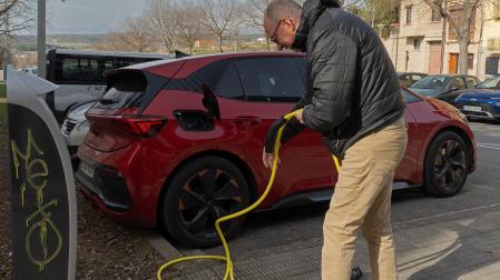 Un automovilista prepara el cable de recarga para enchufar un Cupra Born en una calle de Viana