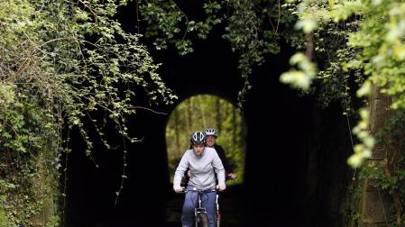 Dos cicloturistas atraviesan un túnel de la Vía Verde del Plazaola.