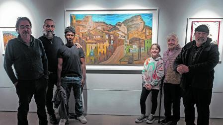 Carmen Lobo, viuda de Retana, con sus hijos y nietos ante una de las obras expuestas, con la calle Navarrería como elemento central.